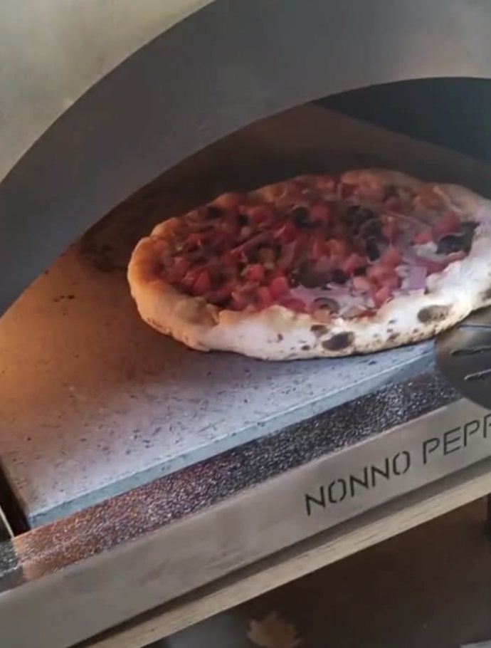 Pizza napolitana sobre la piedra refractaria dentro del horno de leña